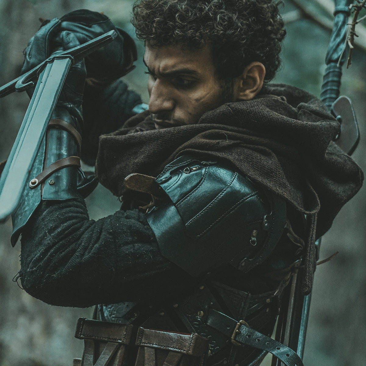 Layering & Accessories for LARP Costumes: Character in dark costume preparing for action with sword.
