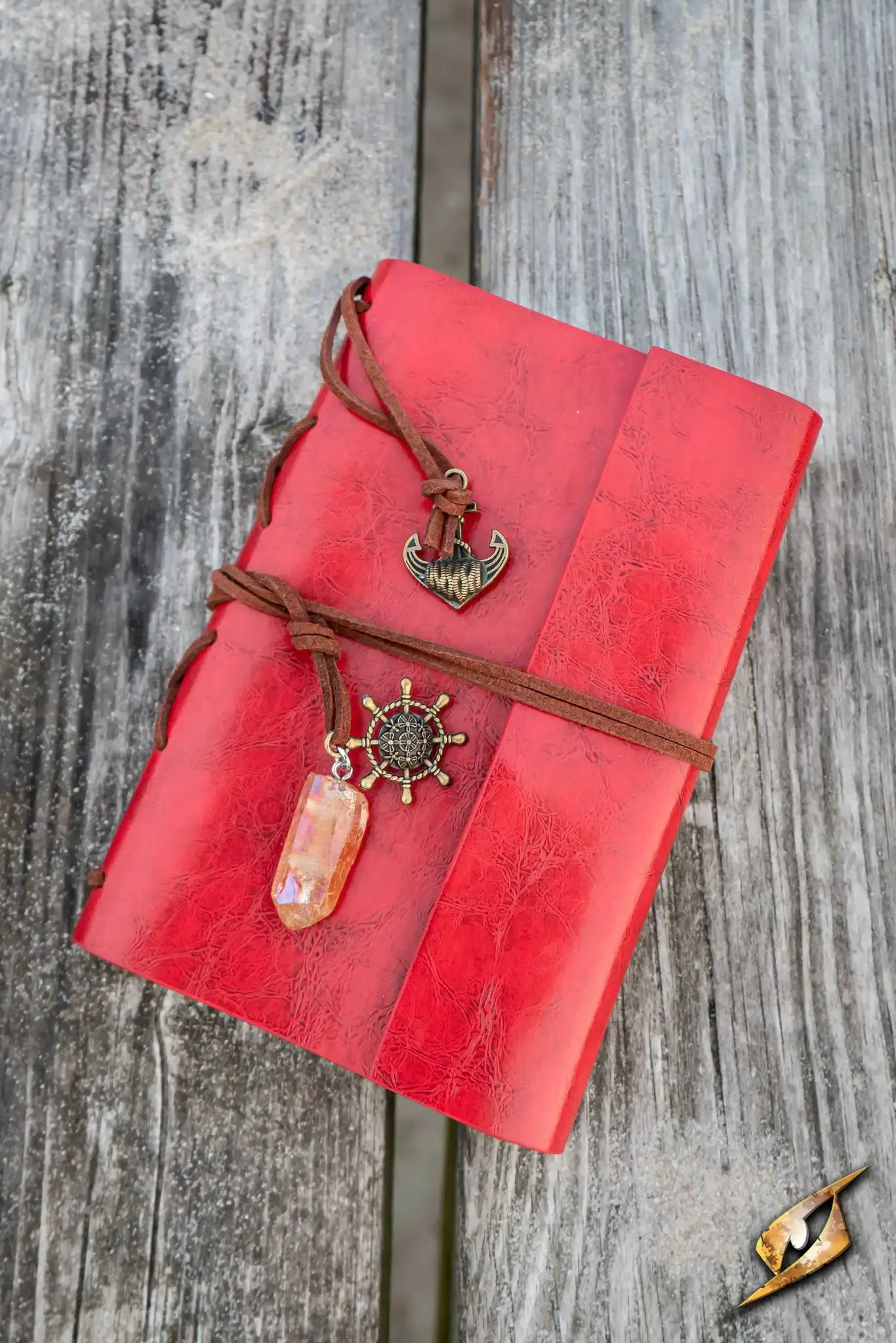 Stationery - red leather journal with charms on a rustic wooden surface.
