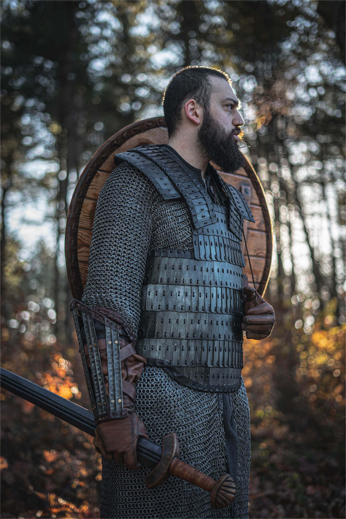 Man wearing Viking Armor with a shield and sword in a forest setting.