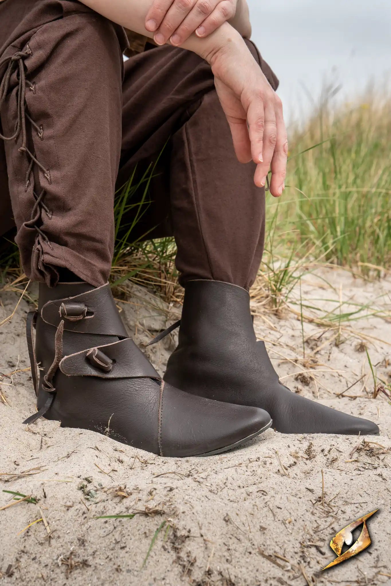 Shoes Jorik displayed on a person sitting in nature, showcasing medieval style and full-grained leather craftsmanship.