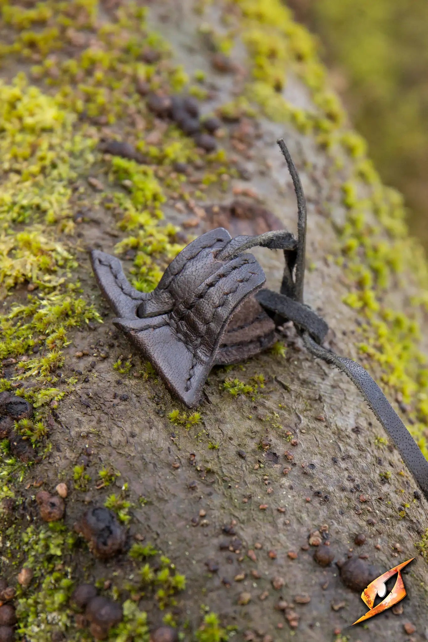 Elven Holster Hook resting on a mossy tree trunk, showcasing its intricate design and craftsmanship.