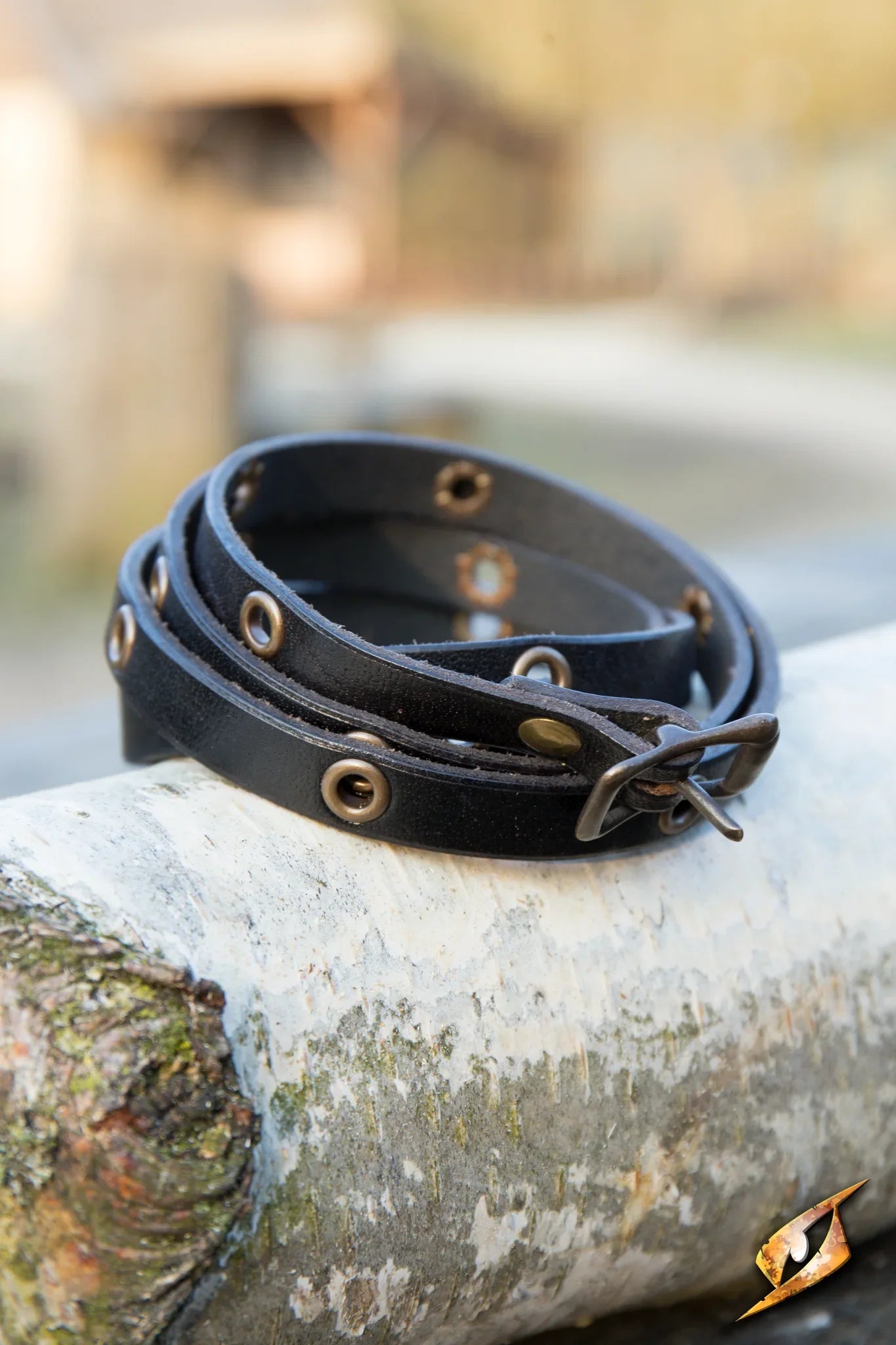 Multistrap Bracelet displayed on a log, showcasing its unique design with decorative features and sturdy material.