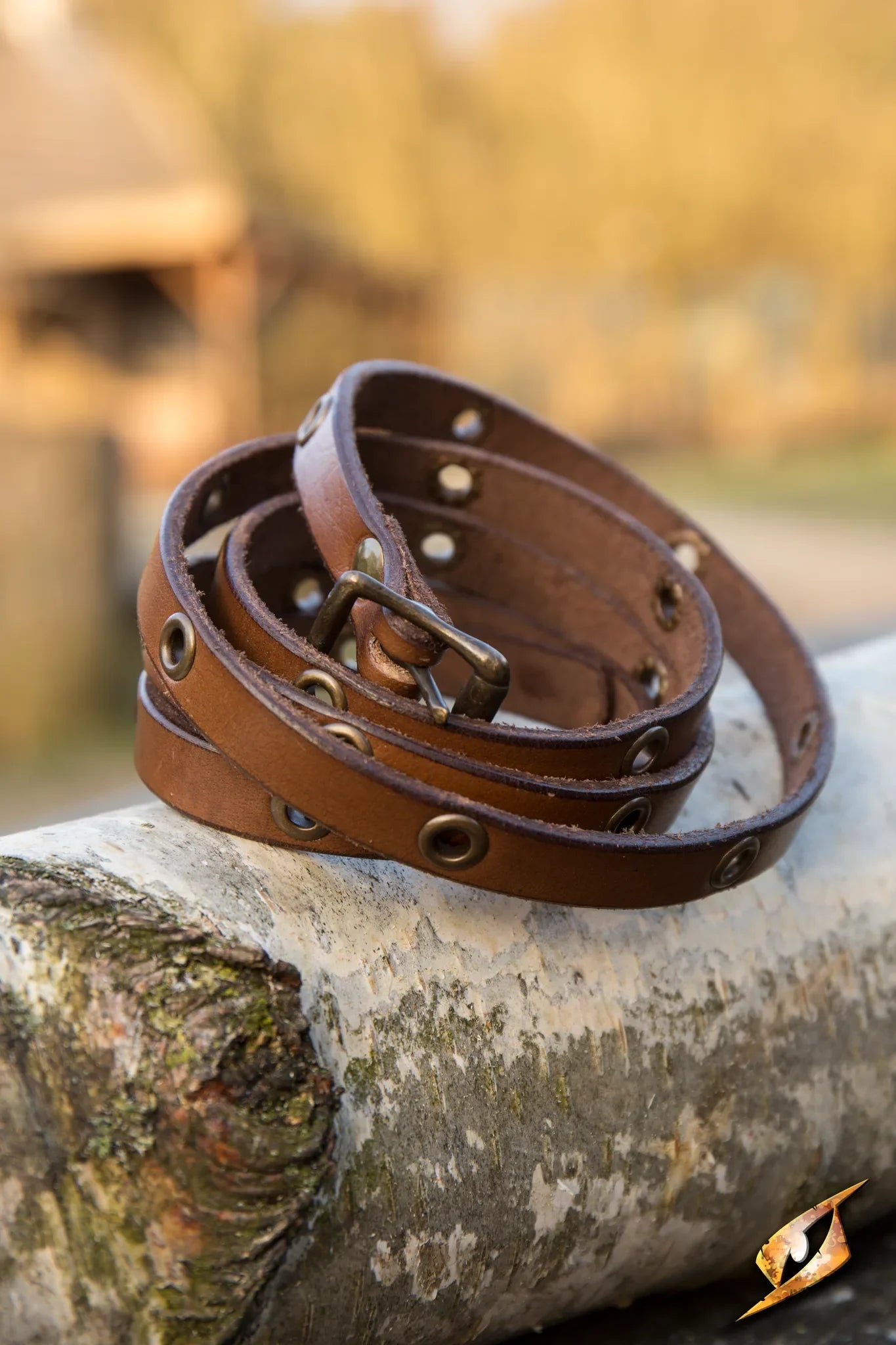 Close-up of a Multistrap Bracelet made of brown leather with metal accents, resting on a wooden surface.