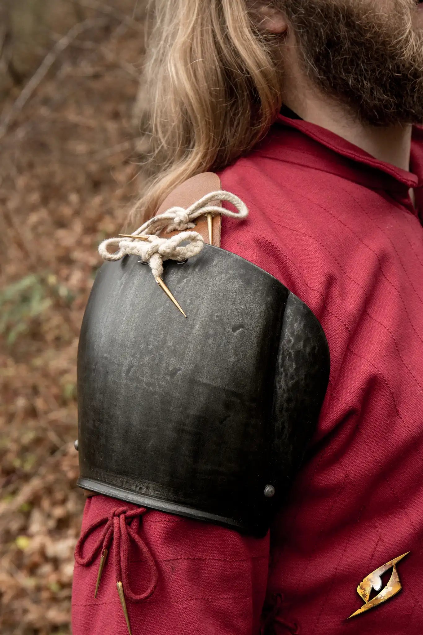 Churburg Shoulders worn by a warrior in a red tunic, showcasing durable steel armor for protection in combat.