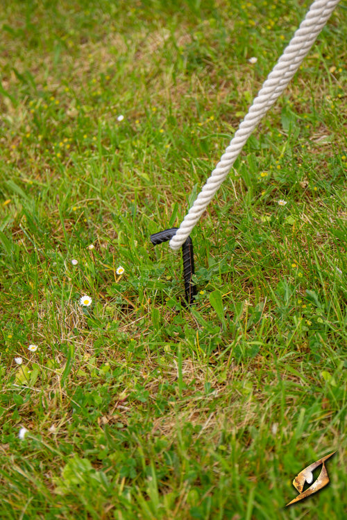 Iron Pegs securing a rope in grass, essential for stabilizing Epic Armoury tents during camping.
