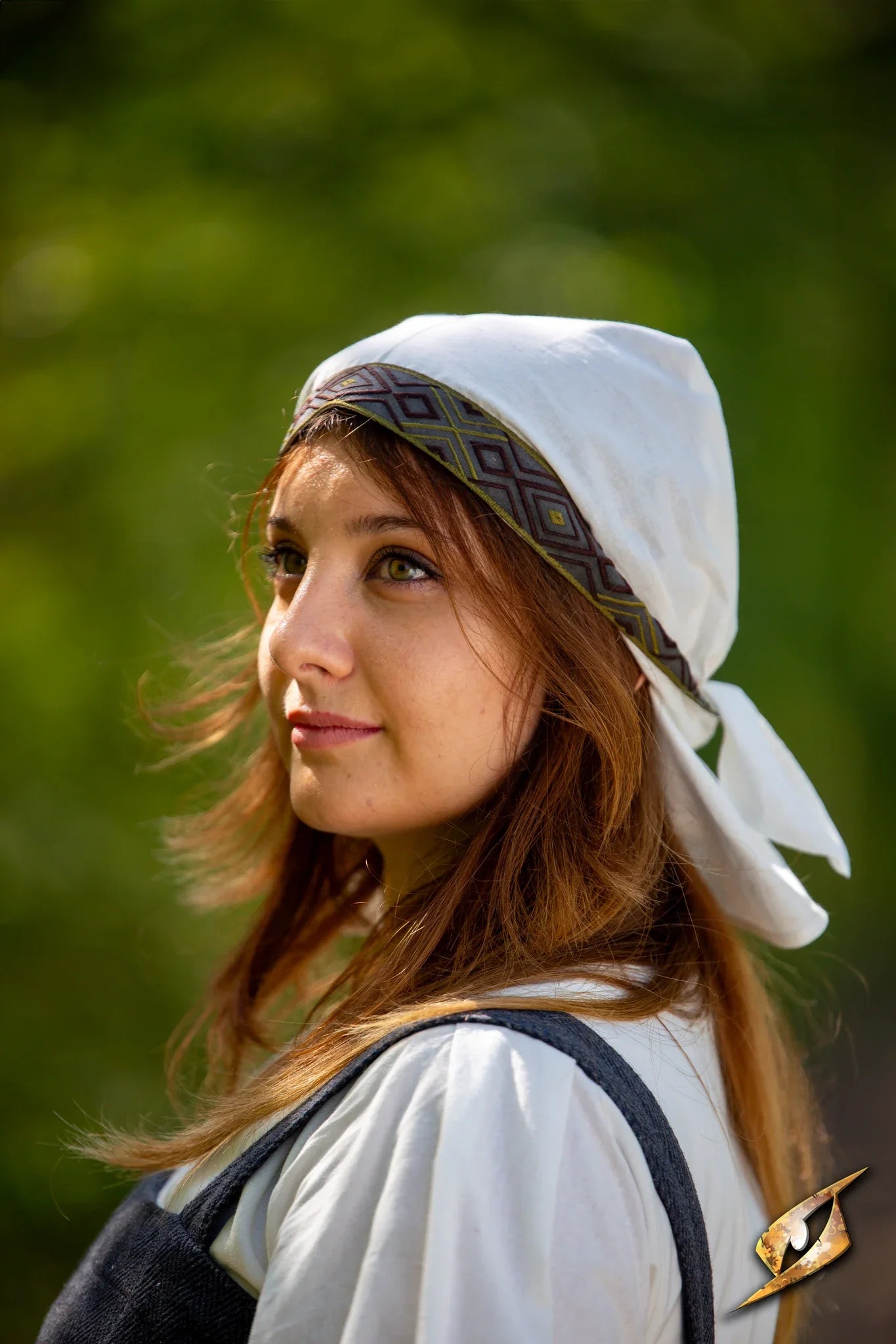 Young woman wearing an Estrid Scarf with intricate patterns, symbolizing resilience and purpose in a natural setting.