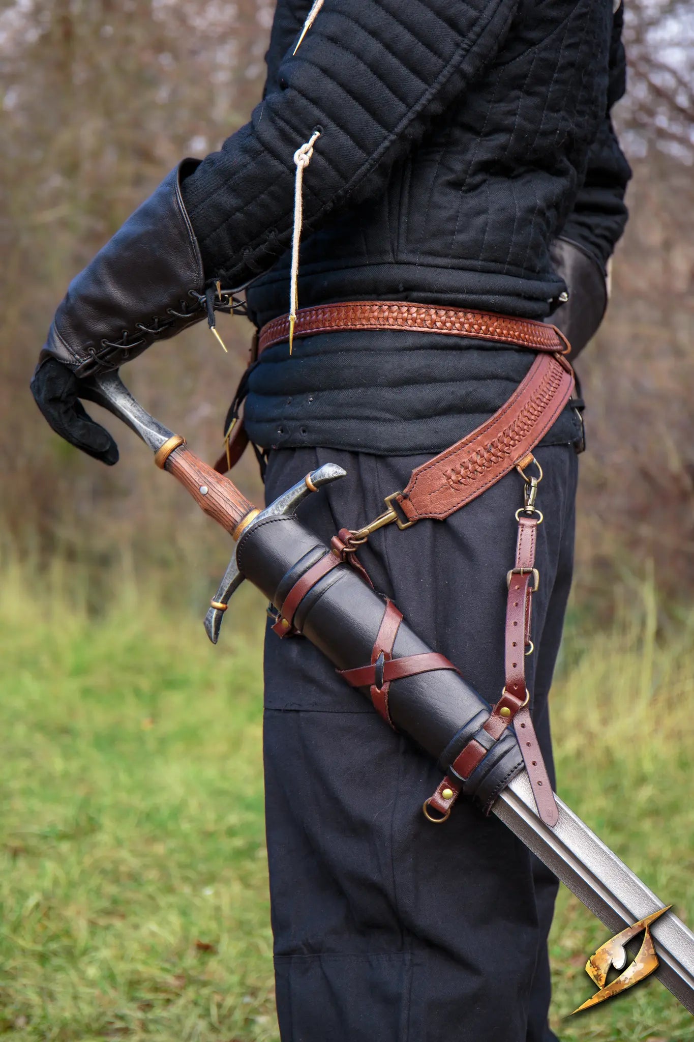 Man standing with a sword fitted in a stylish sword belt hanger, showcasing leather craftsmanship.