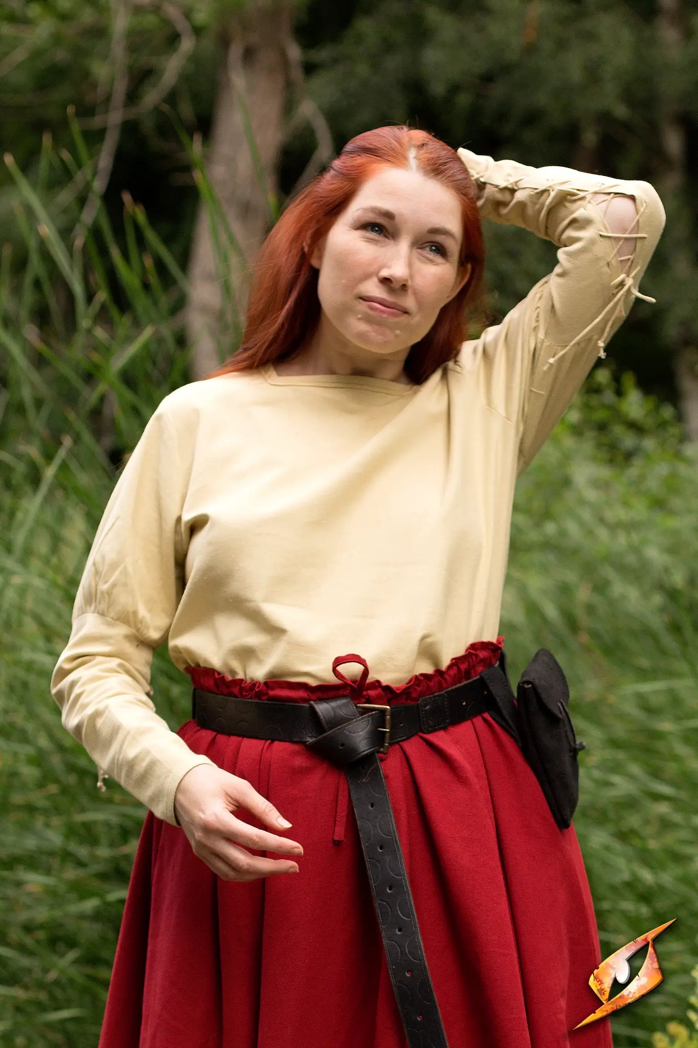 A model wears an Empire Shirt with puffy shoulders, paired with a red skirt in a natural setting.