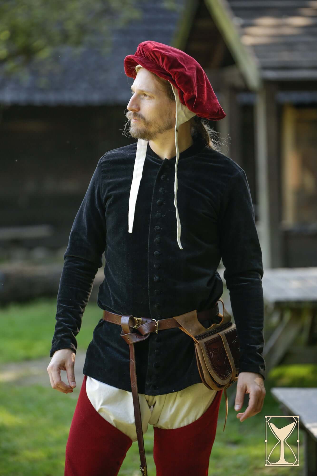 Man wearing Cotehardie Bonifacio with a red hat, showcasing sharp fit and comfortable design in historical setting.