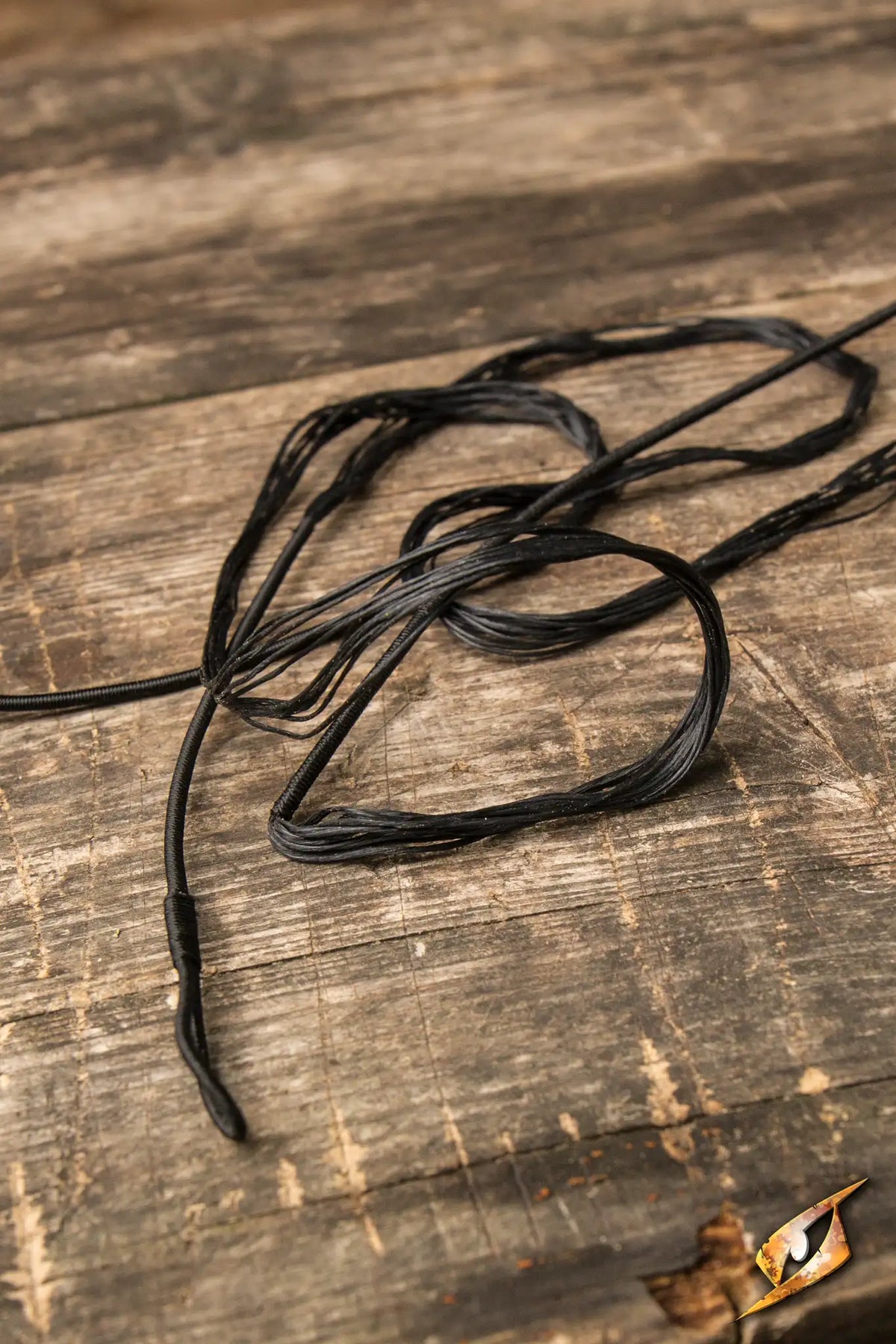 Bow String on a wooden surface, showcasing the durable replacement for Epic Armoury’s Medium LARP Flatbow.