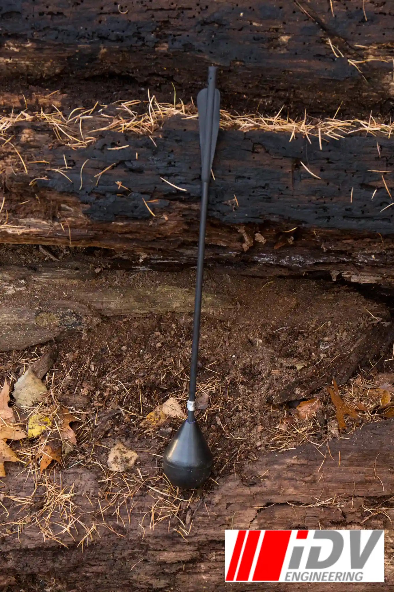 Bolt - Round Head - 15" - Black/Black resting on the ground among leaves and logs, designed by iDV Engineering.