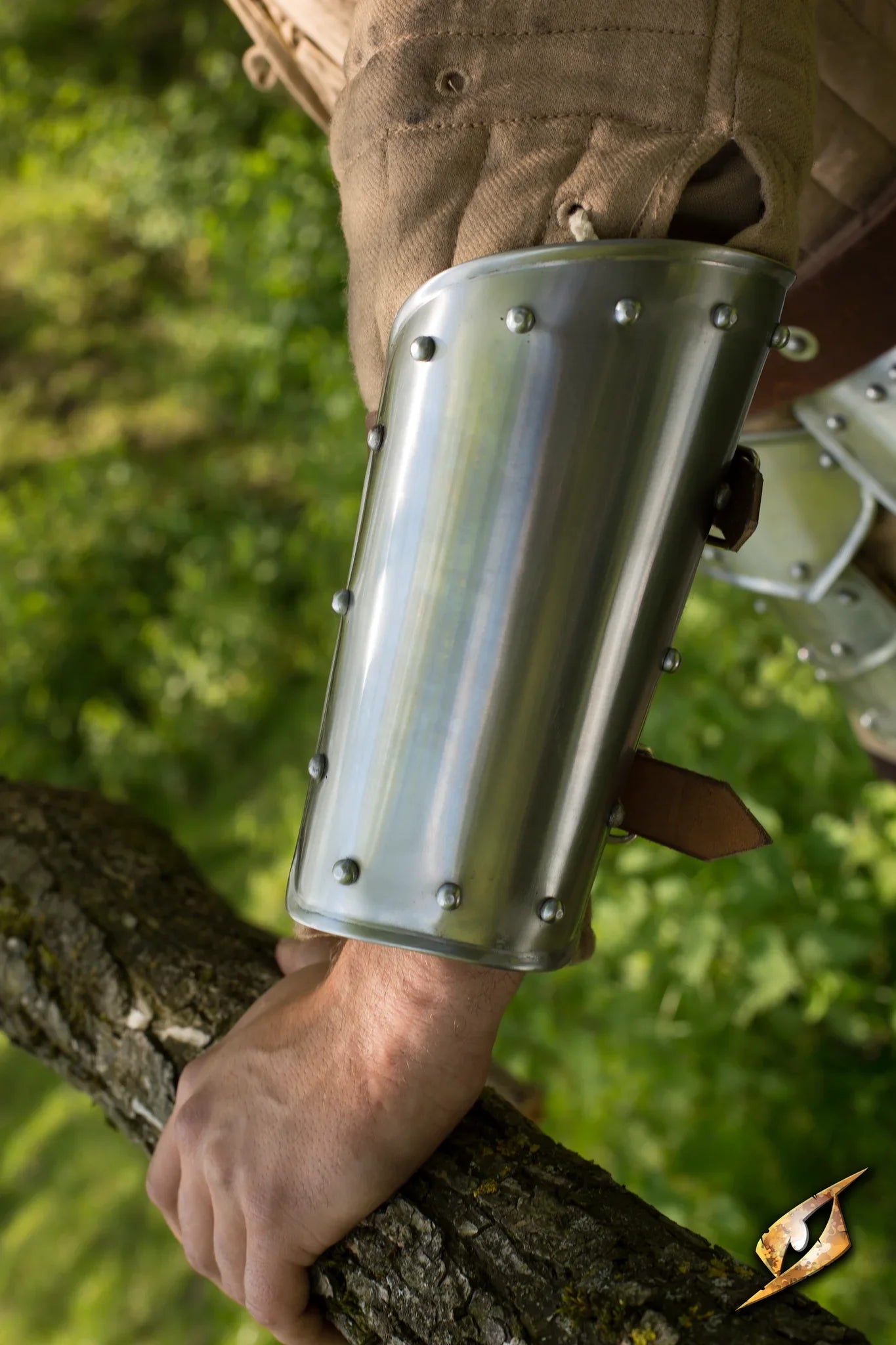 Arm Protection Warrior: Close-up of sturdy metal arm guard worn on a soldier's arm amidst lush greenery.