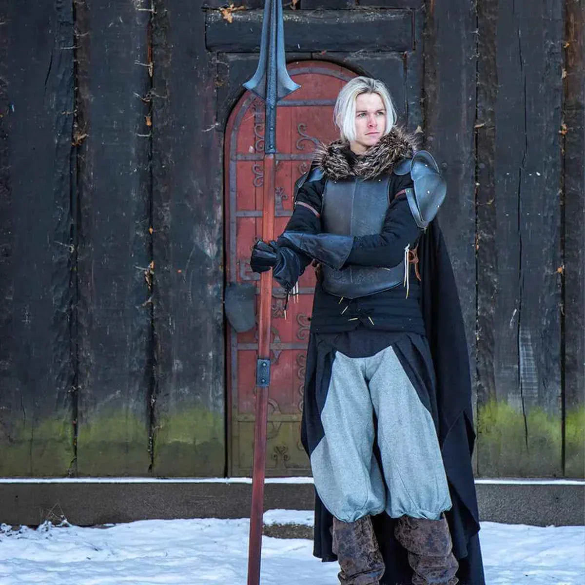 A warrior in armor holding a spear stands confidently in the snow, showcasing their compact gear for a fantasy setting.