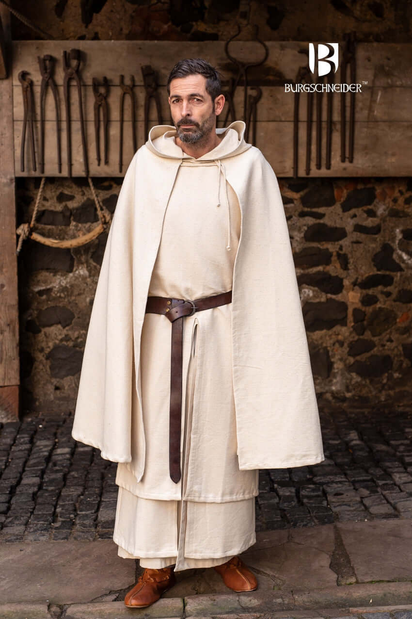 A man in a medieval outfit by Burgschneider, wearing a cloak and sandals, standing in a stone courtyard.