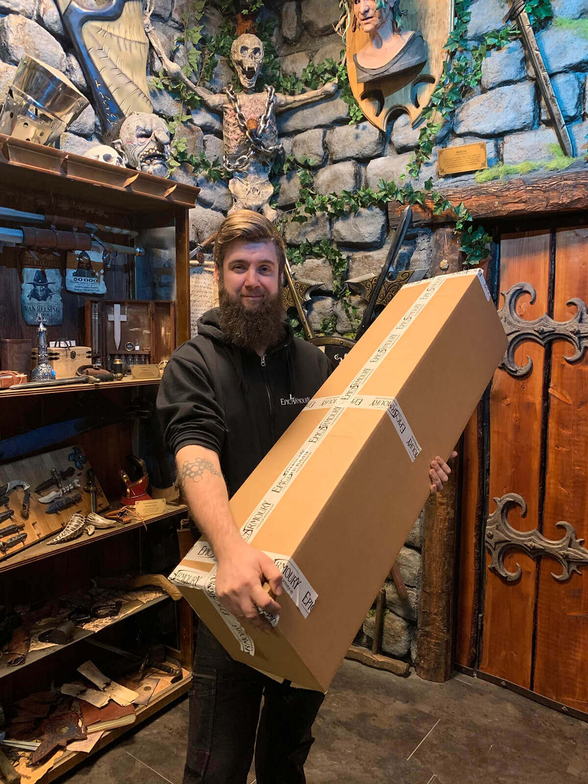 Man holding a large box in an outlet shop filled with unique and discounted items from the Outlet collection.