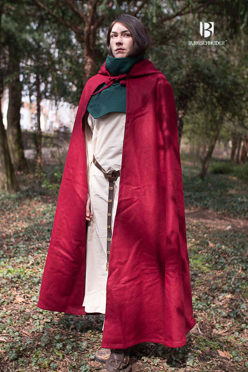 Wool Hooded Cloak Hibernus in red, worn outdoors, showcasing medieval style with a pointed hood and clasp.