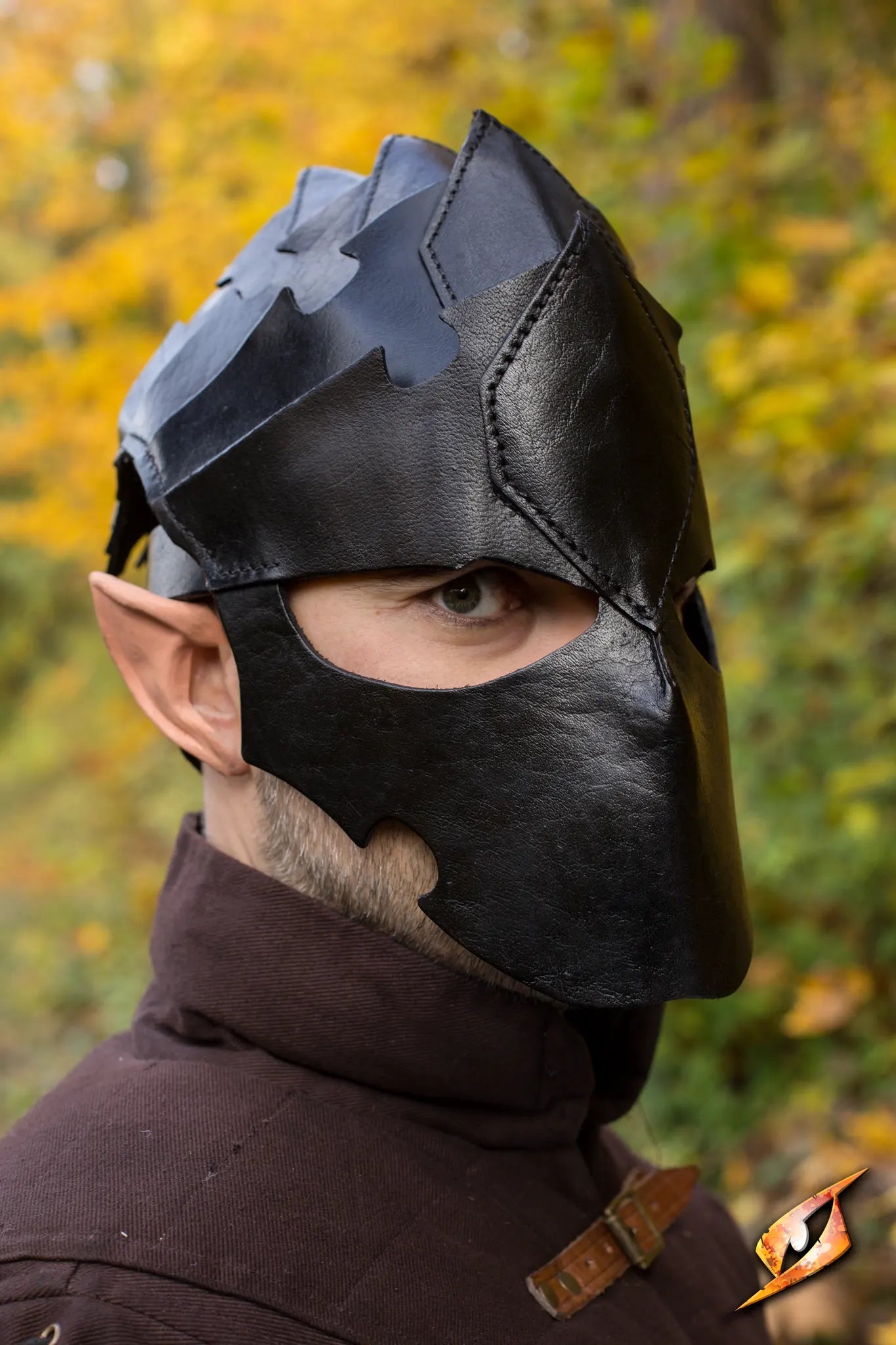 Close-up of a man wearing an Assassin Helmet, showcasing its detailed design against a backdrop of autumn leaves.