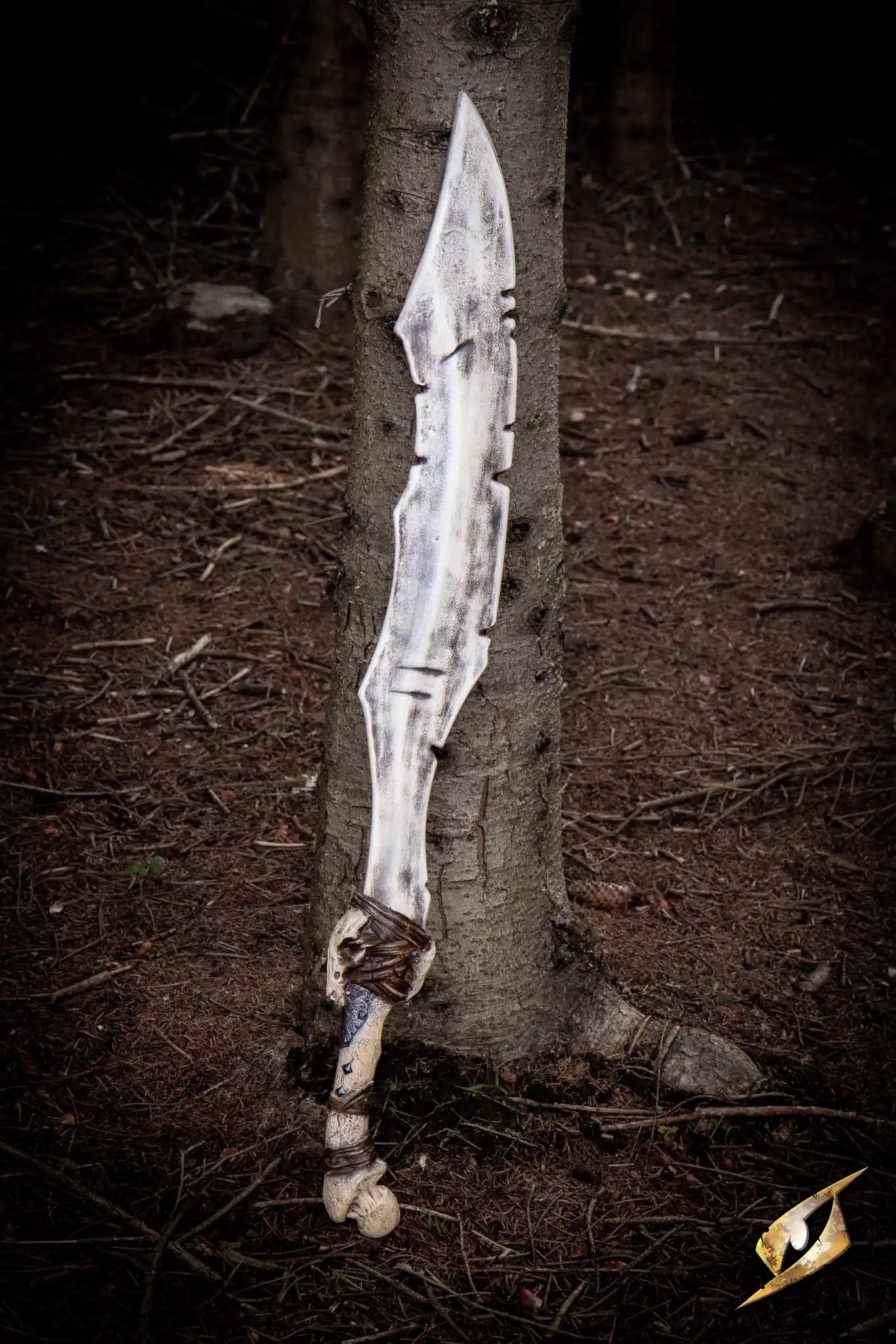 Bone Chopper - 100 cm. sword leaning against a tree in a forest setting, showcasing its unique design.