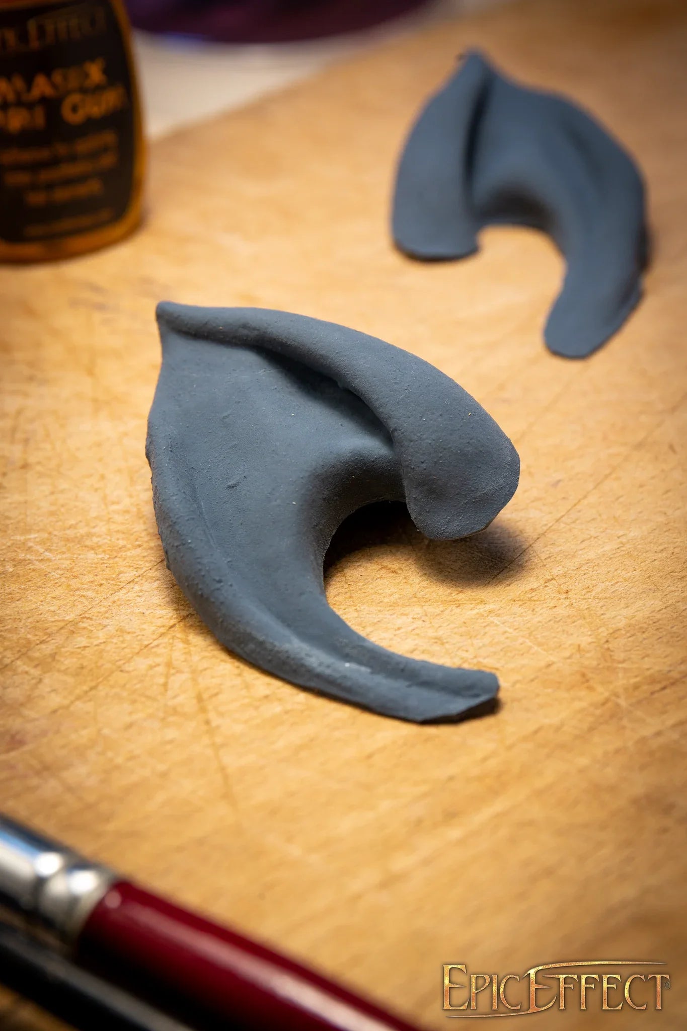 Dark Elf Ears displayed on a wooden surface, showcasing their unique shape and texture for fantasy costume designs.