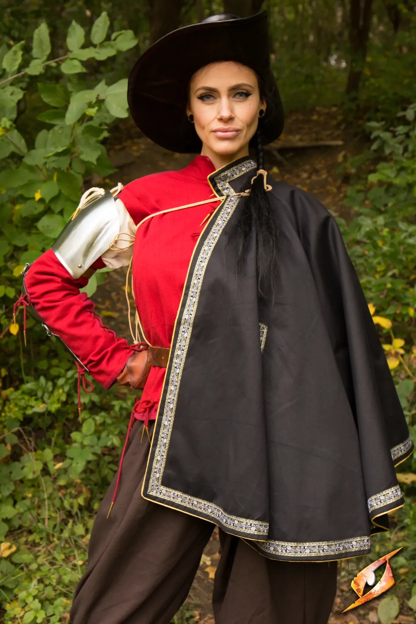 Cape Aramis worn by a model with high collar cape, red attire, and decorative trim in an outdoor setting.