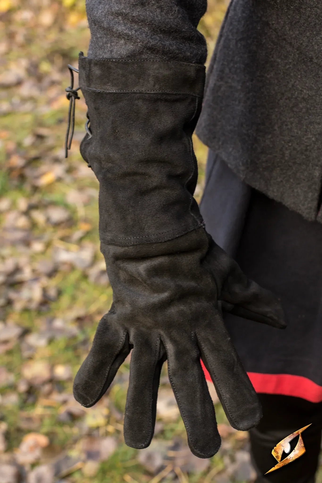 Close-up of a hand wearing stylish black Leather Gloves on a blurred autumn leaf background.