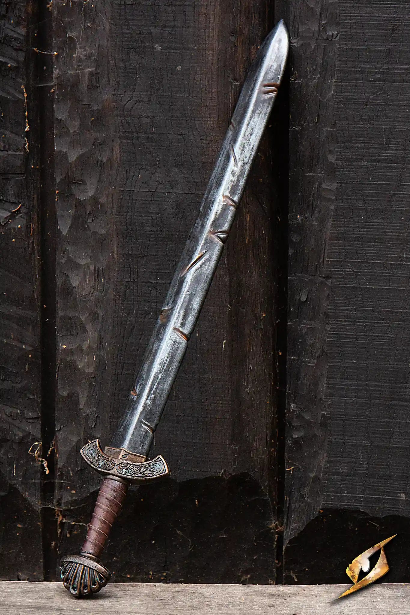 Battleworn Viking Sword displayed against a dark wooden backdrop, showcasing its fullered blade and detailed handle.