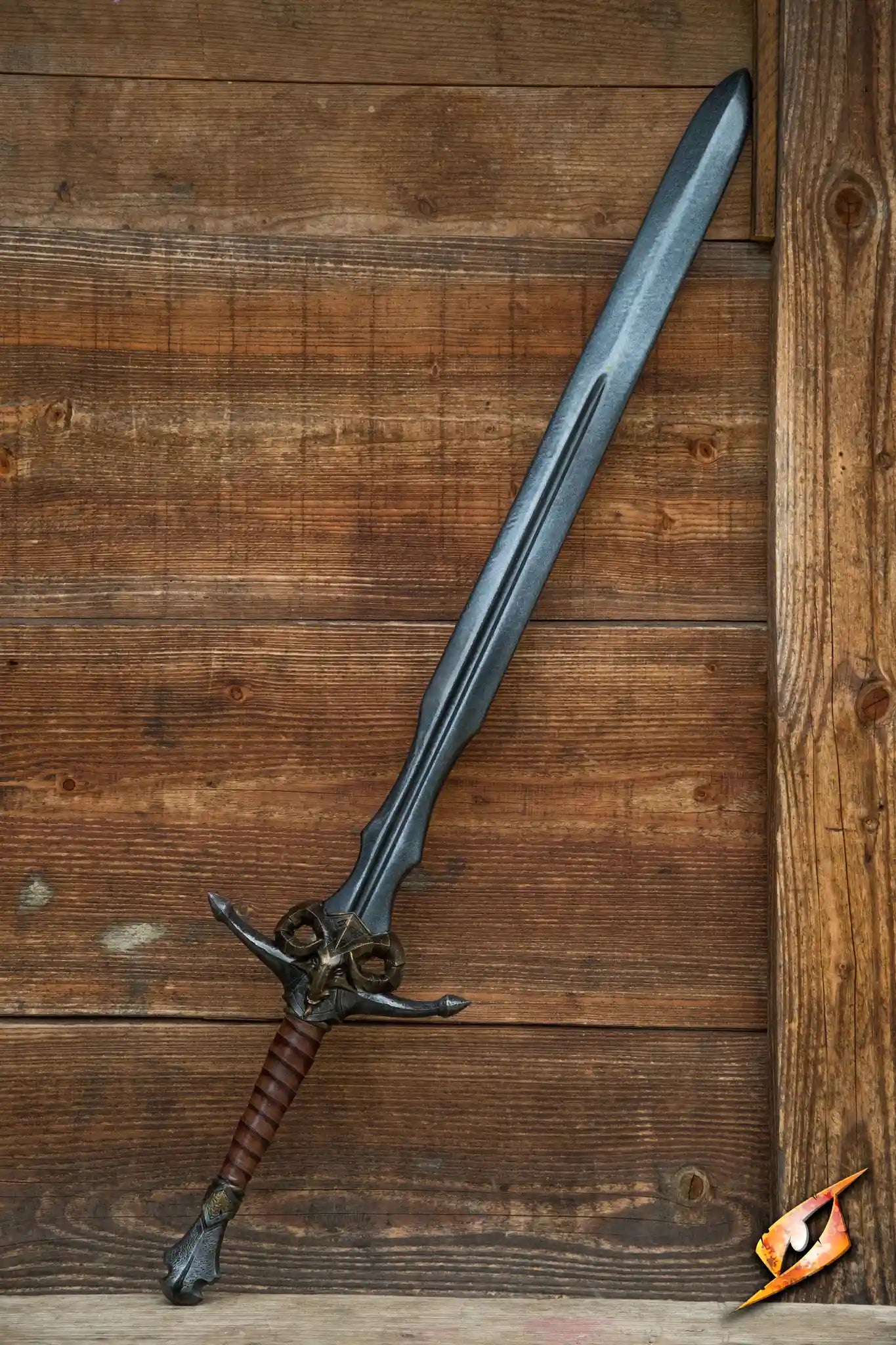 Caprine Sword displayed against a wooden background, featuring a latex blade and a brass ram hilt.