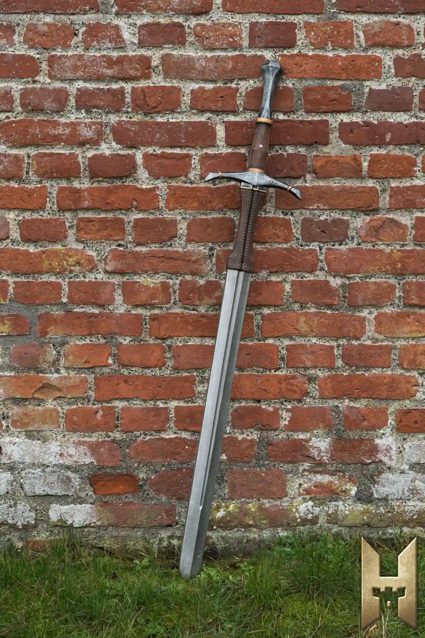 Bastard Sword resting against a brick wall, showcasing its impressive design and craftsmanship.